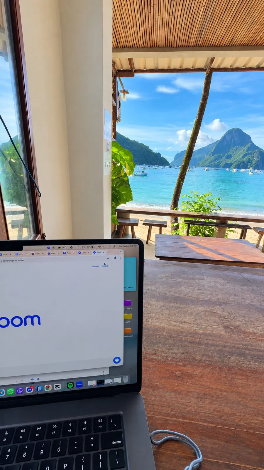 A MacBook open on a beachfront café table looking out over the bay